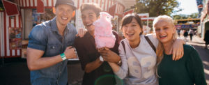 Group of young friends with cotton candy in amusement park